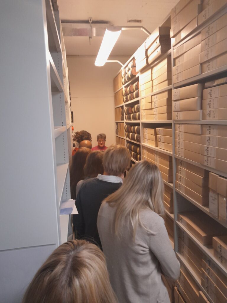 Fotografi: Medarbetare på Läkarförbundet står inträngda i utrymmet mellan två kompakthyllor. På hyllorna står arkivvolymer av olika slag.